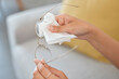 Hands, person and cleaning vision glasses with tissue for lens protection, sight and eye care safety at home. Closeup, cloth and wipe dirt on clear spectacle frames, eyewear and eyesight for wellness