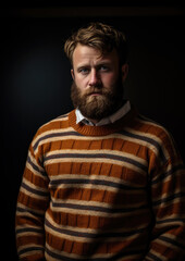 Poster - A Portrait of a Man Wearing a Brown Striped Knitted Jumper on a Black Background