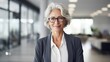 © Stock 4 You - Mature business woman looking at camera indoors at work with copy space. Senior smiling European 50s 60s years businesswoman professional standing confident in modern coworking creative office space.