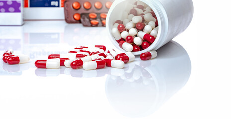 Poster - Red and white capsules pill spilled out from white plastic bottle. Prescription drug. Healthcare and medicine. Antibiotics drug. Antimicrobial capsule pills. Pharmaceutical industry. Pharmacy product.