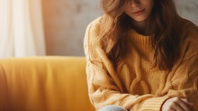 Serene young woman in a knitted wool sweater is resting at home on an autumn or winter day. Concern for mental health, loneliness, a sense of balance and calmness with sun light