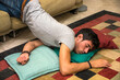 Photo of a young and handsome man resting in a strange position on the floor with a pillow under his head, maybe drunk or very tired