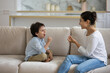 © fizkes - 5s boy with smiling Indian mother or teacher therapist doing exercise, language and speech development, caring young mom and son child engaged in educational activity, sitting on couch at home