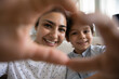 © fizkes - Smiling Indian mother and 5s son showing looking through heart shape gesture with fingers at camera, taking selfie, young mom with adorable boy child expressing love, happy motherhood concept