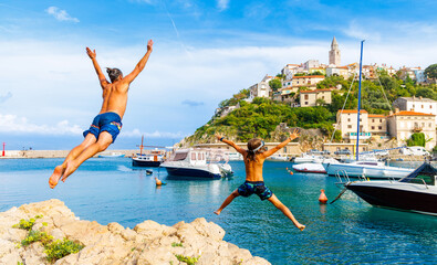 Happy family jumping off the rock into the sea, beautiful beach in Croatia (Croatia,Europa)