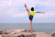 young slender girl throwing her leg in the air during gymnastic exercises on the rocks