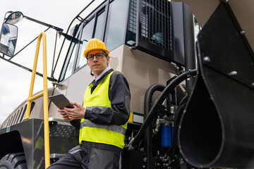 Poster - Engineer with tablet computer stands on the stairs to the cab of a truck.