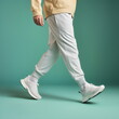 male legs side view wearing white sneakers isolated on plain green studio background