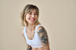 © insta_photos - Smiling blond pretty happy girl beauty female generation z tattooed model with short blonde hair beautiful face healthy skin looking at camera laughing isolated at beige background. Aesthetic portrait