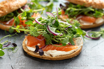 Smoked salmon and soft cheese seeded bagel with pea and purple reddish shoot salad and red onion. Protein packed breakfast concept