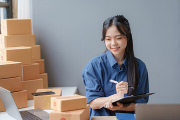 Wall Mural - E-commerce Entrepreneurship. Asian Female Online Seller Packing Orders for Internet Sales. Efficient Online Sales. Asian Female owner Packaging Products for Delivery.