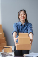 Wall Mural - E-commerce Entrepreneurship. Asian Female Online Seller Packing Orders for Internet Sales. Efficient Online Sales. Asian Female owner Packaging Products for Delivery.