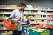 © Serhii - Closeup portrait, handsome young man picking up bell peppers, choosing yellow and orange vegetables in grocery store