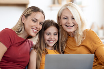 Wall Mural - Happy family mother, daughter and grandmother using laptop at home