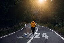 Man running on the mountain road towards new goals in 2024. New Year 2024 with new ambitions, challenge, plans, goals and visions.