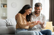 © Home-stock - Happy indian spouses holding positive pregnancy test, sitting on couch at home together, couple celebrating awaiting baby, copy space