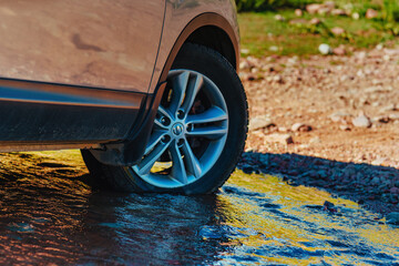 Canvas Print - Car wheel standing offroad in a mountain creek close-up view