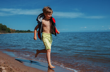 Sticker - Happy boy in vest and shorts running along lake shore at summer