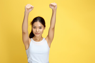 Woman in white tank top is raising her arms. This versatile image can be used to portray joy, celebration, victory, or exercise.