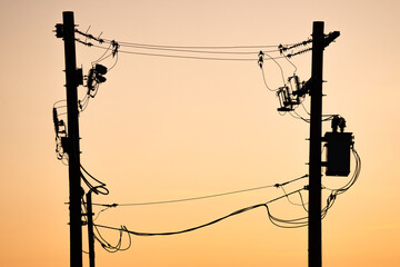 power pole silhouette of transmission lines at sunset in alberta canada.