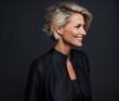 © Restyler - Studio portrait of a middle-aged blond smiling woman in a black blouse on a dark background. Business style.