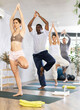 Young woman doing yoga exercises in multiethnic group in fitness studio