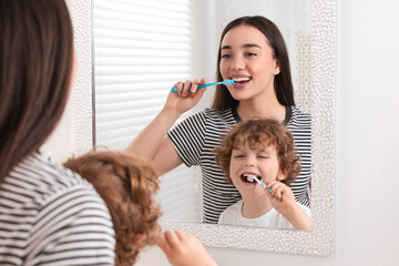 Wall Mural - Mother and her son brushing teeth together near mirror in bathroom