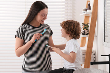 Wall Mural - Mother and her son brushing teeth together in bathroom