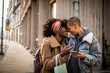 © Marko Geber - Young interracial lesbian couple shopping and using a phone in the city