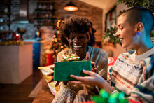 Young interracial lesbian couple gifting presents during christmas and the new year holidays at home
