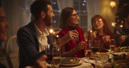 Wall Mural - Portrait with Parents, Children and Friends Enjoying Christmas Dinner Together in a Cozy Home in the Evening. Relatives Sharing Meals, Singing Traditional Festive Songs and Burning Sparkles