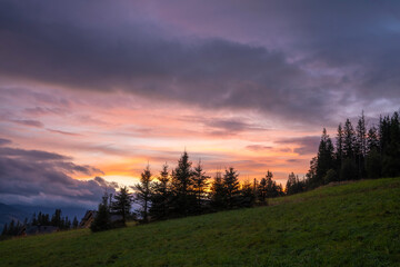 Wall Mural - beautiful dramatic coloured sky over a meadow in the mountains