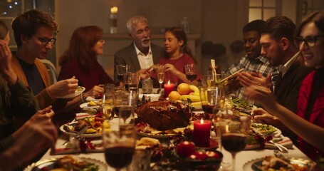 Wall Mural - Diverse Group of Relatives and Friends Sitting Together Behind a Dining Table with Tasty Meals and Festive Winter Decorations. Big Happy Family Having Fun conversation, Enjoying a Holiday Evening