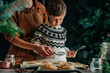 © Westend61 - Mother and son dusting sugar on cinnamon buns at table