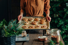 Woman Holding Cinnamon Buns In Tray At Home