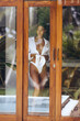 Spying of young sexy woman in dressing up elegant white lingerie and shirt through window glass on private tropical villa 