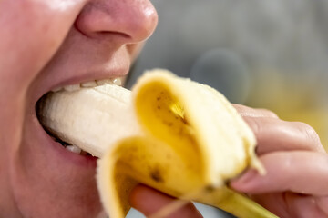 Poster - An adult woman eats a banana, close-up.