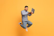 © Prostock-studio - Online Offer. Happy Young Asian Man With Laptop Jumping Over Yellow Background