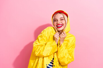 Wall Mural - Photo of funky cheerful good mood girl hiding rain dressed yellow waterproof clothes empty space isolated on pink color background