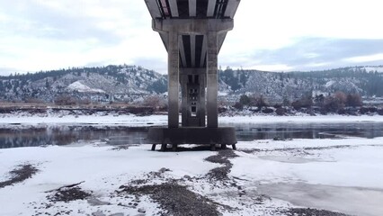 Poster - Drone flies over the South Thompson River through the arches of the Lafarge Bridge on a winter day