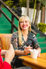 Wall Mural - Adult female blonde model enjoying ice cream while sitting at the park cafe