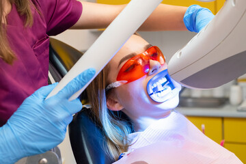 Wall Mural - Teeth whitening, including the application of a UV lamp for bleaching, is performed for a woman at the dentists clinic.