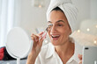Smiling woman doing makeup with eyelash curler