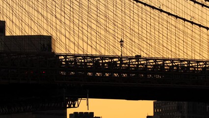 Wall Mural - Traffic on Brooklyn Bridge. 4K video with people and cars silhouette against orange sunset sky with this landmark building from Manhattan, New York.