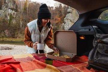 Poster - happy woman eating pizza drinking tea with view of autumn carpathian river