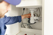 Close up of professional plumber installs a siphon pipe on the kitchen sink