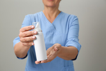 Sticker - Woman holding nasal spray against light grey background, closeup