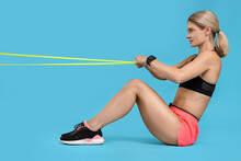 Woman Exercising With Elastic Resistance Band On Light Blue Background