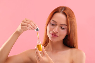 Poster - Beautiful young woman with bottle of cosmetic serum on pink background