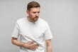 © DimaBerlin - Man holds on to sore stomach. Unwell guy experiences nausea, suffers from symptoms of gastritis, acute pain in stomach, intestines, discomfort, unpleasant feeling, ache in abs after exercise, sports.